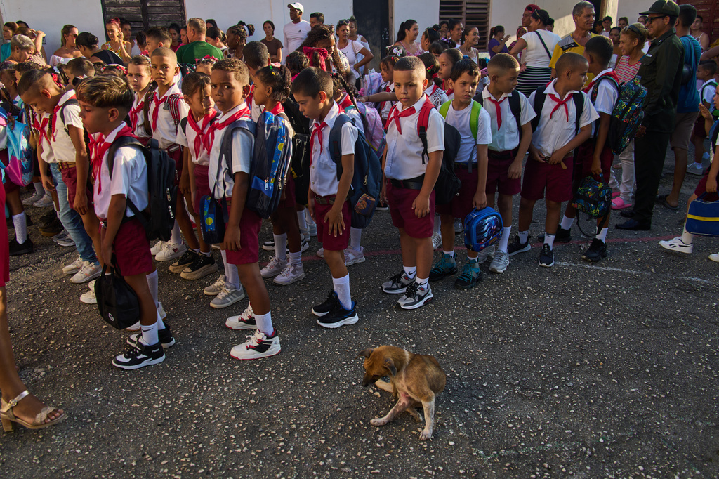 Children line up for their national anthem in the school courtyard where a stray dog sits by on the first day back to school in Minas, Cuba's Havana province, Tuesday, Sept. 1, 2026. (AP Photo/Ramon Espinosa)