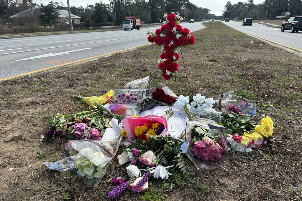 Flowers left in memory of Linda Davis lie by the roadway Thursday, Feb. 19, 2026, at the site outside Savannah, Ga., where Davis was killed in a crash. (AP Photo/Russ Bynum)