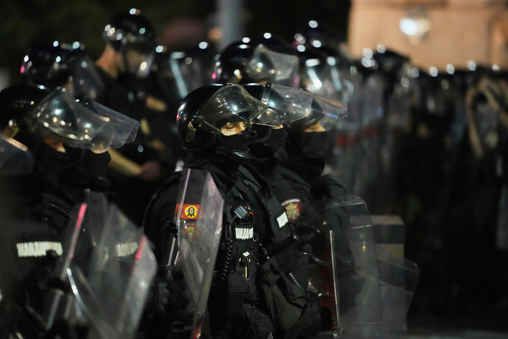 A Serbian gendarmerie officer with a sticker depicting Jesus Christ stands in cordon separating protesters from opposing camps during an anti-government protest in Belgrade, Serbia, Wednesday, Aug. 13, 2025. (AP Photo/Darko Vojinovic)