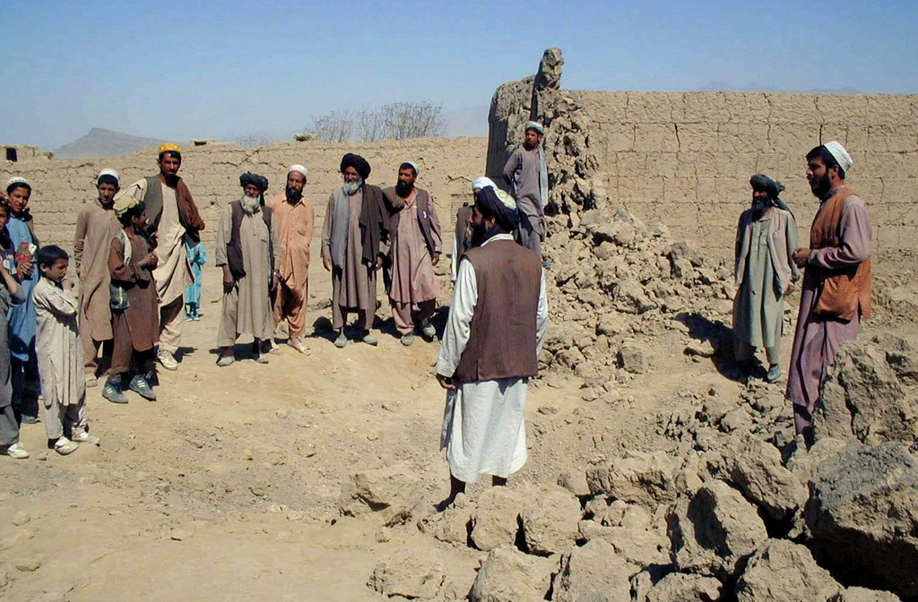 FILE - Residents look at the damage caused by a U.S. air strike in the village of Deh Sabz, north of the Afghan capital Kabul on Oct. 10, 2001. (AP Photo/Amir Shah, File)