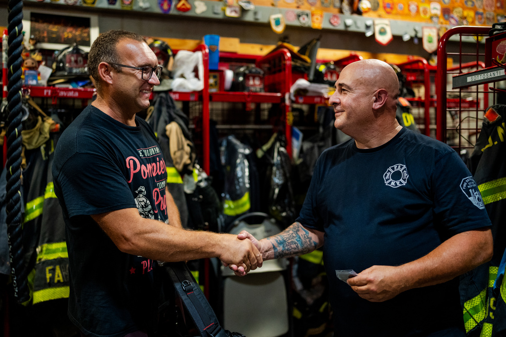 Firefighter Sal Argano, right, Ladder 10, greets Laurent Cosenefroy, a volunteer firefighter from France visiting New York and the FDNY "Ten House" for his birthday, Friday, Aug. 7, 2026, in New York. (AP Photo/Angelina Katsanis)