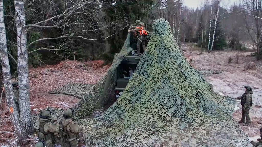 In this image made from video provided by Russian Defense Ministry Press Service on Monday, Dec. 29, 2025, Russian solders camouflage one of the trucks of the Russia's Oreshnik missile system with a net during training in an undisclosed location in Belarus. (Russian Defense Ministry Press Service via AP)