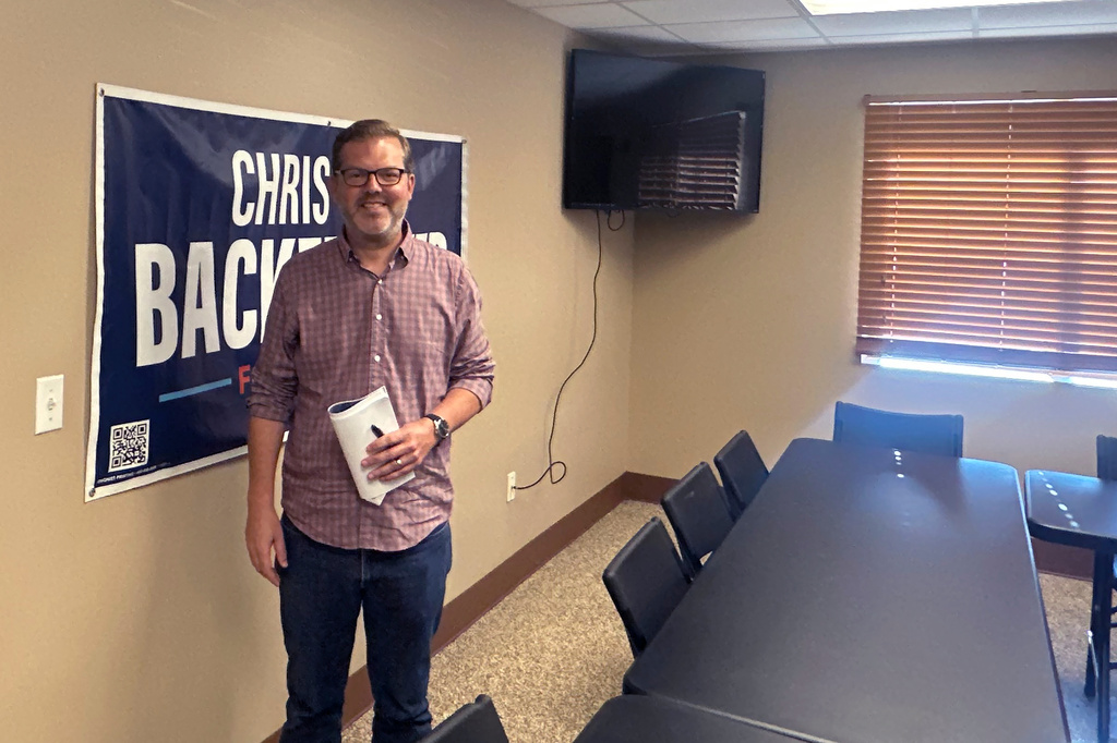 Democratic congressional candidate Chris Backemeyer poses in front of a campaign banner after an event in Murdock, Nebraska, on Sunday, Aug. 16, 2026. (AP Photo/Will Weissert)