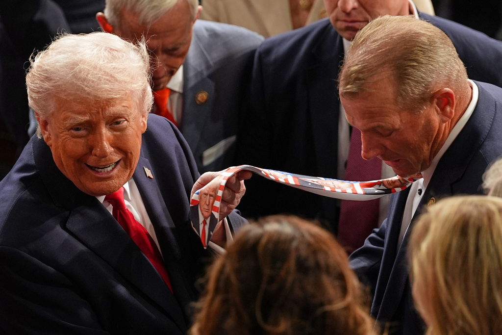 President Donald Trump holds up Rep. Troy Nehls, R-Texas, tie with his face as he departs after delivering the State of the Union address to a joint session of Congress in the House chamber at the U.S. Capitol in Washington, Tuesday, Feb. 24, 2026. (AP Photo/Matt Rourke)