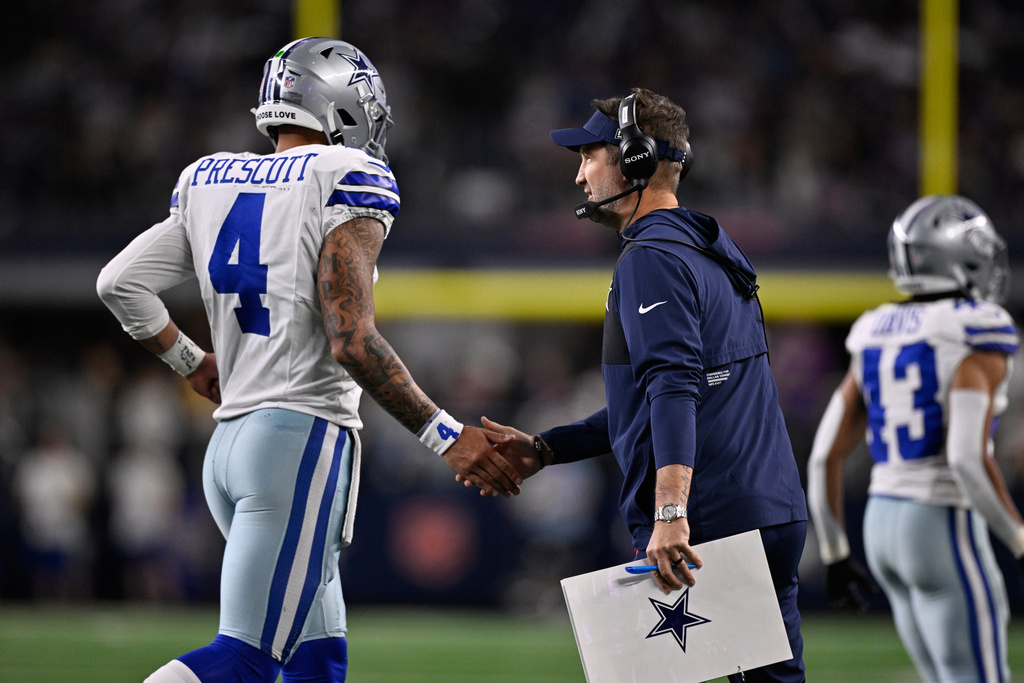Dallas Cowboys quarterback Dak Prescott (4) celebrates with head coach Brian Schottenheimer after a touchdown during the first half of an NFL football game against the Minnesota Vikings Sunday, Dec. 14, 2025, in Arlington, Texas. (AP Photo/Jerome Miron)