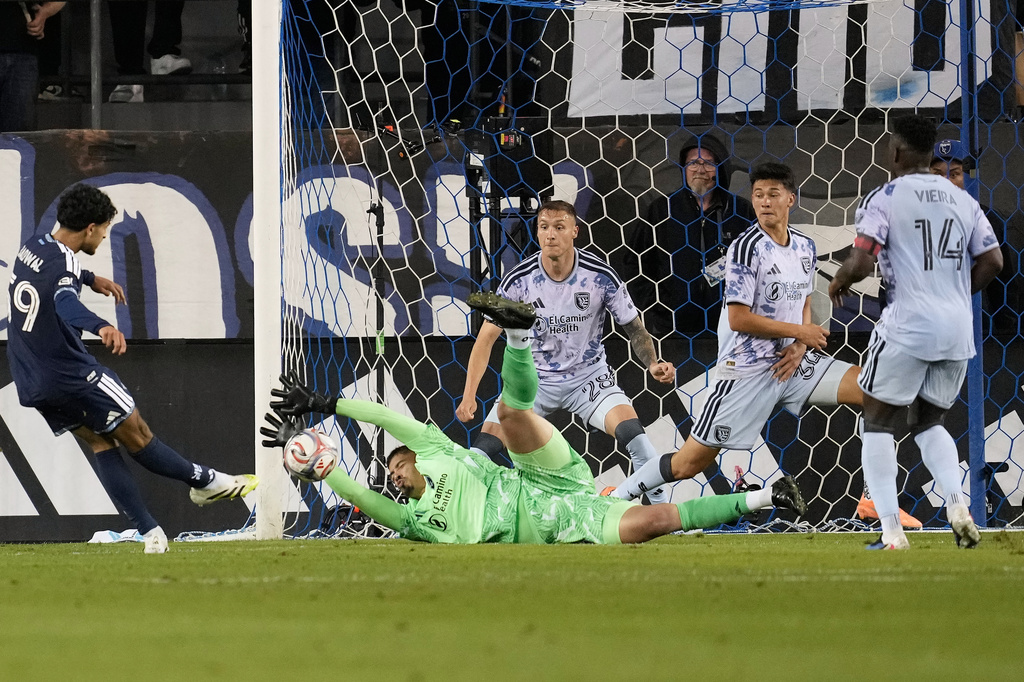 San Jose Earthquakes goalkeeper Daniel de Sousa Britto, bottom, defends a shot by Vancouver Whitecaps midfielder Jeevan Badwal, left, during the second half of an MLS soccer match Saturday, May 9, 2026, in San Jose, Calif. (AP Photo/Jeff Chiu)
