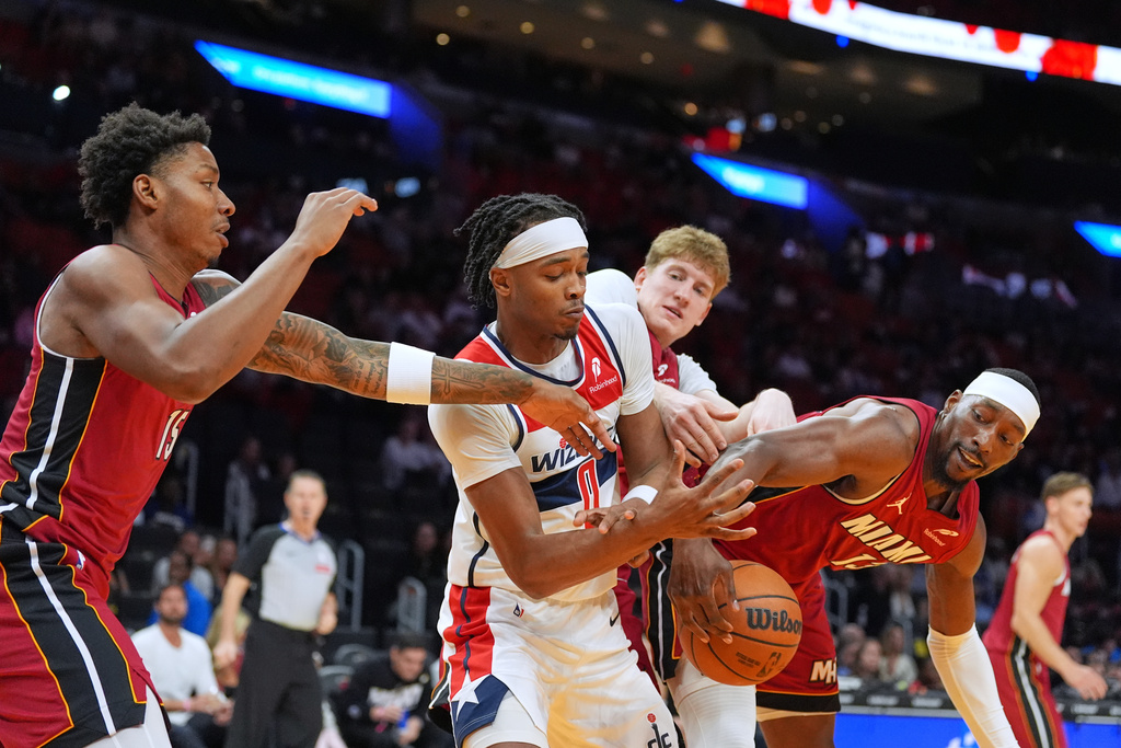 Washington Wizards guard Bilal Coulibaly (0) is stripped of the ball by Miami Heat center Bam Adebayo, right, as forward Myron Gardner (15) and guard Kasparas Jakucionis, back, also defend during the first half of an NBA basketball game, Tuesday, March 10, 2026, in Miami. (AP Photo/Rebecca Blackwell)