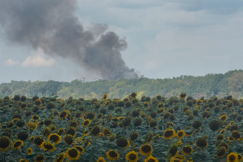 Smoke rises above warehouse stores behind a sunflower field following a Russian air attack in Kyiv, Ukraine, Thursday, Aug. 27, 2026. (AP Photo/Efrem Lukatsky)