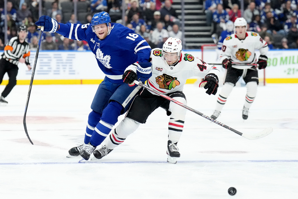 Toronto Maple Leafs forward Steven Lorentz (18) and Chicago Blackhawks defenceman Wyatt Kaiser (44) vie for control of the puck during the second period of an NHL hockey game in Toronto, Tuesday, Dec. 16, 2025. (Nathan Denette/The Canadian Press via AP)
