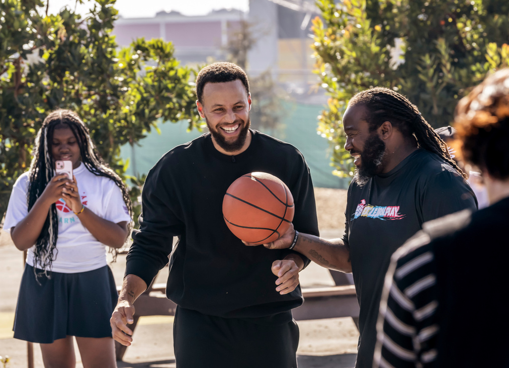 Warriors star Stephen Curry plays a little basketball with students during an event for his Eat.Learn.Play. Foundation at Madison Park Academy Primary in Oakland, Calif., on Wednesday, Sept. 23, 2026. (Carlos Avila Gonzalez/San Francisco Chronicle via AP)
