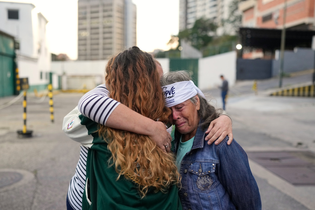 Flor Zambrano, whose son, Rene Chourio, she says is detained at Zone 7 of the Bolivarian National Police for political reasons, embraces relatives of other detainees outside the facility in Caracas, Venezuela, Monday, Jan. 12, 2026. (AP Photo/Matias Delacroix)