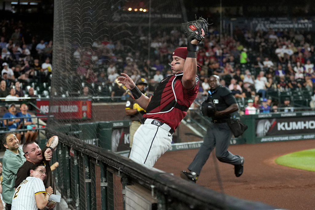Arizona Diamondbacks catcher James McCann, center, makes a foul ball catch against San Diego Padres' Fernando Tatis Jr. as home plate umpire umpire James Jean looks on during the first inning of a baseball game, Wednesday, Aug. 5, 2026, in Phoenix. (AP Photo/Ross D. Franklin)