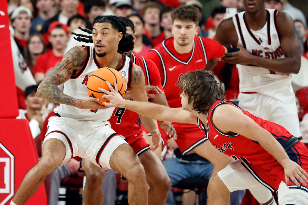 North Carolina State's Alyn Breed (7) controls the ball with Liberty's Colin Porter (0) reaching in during the first half of an NCAA college basketball game in Raleigh, N.C., Wednesday, Dec. 10, 2025. (AP Photo/Karl DeBlaker)