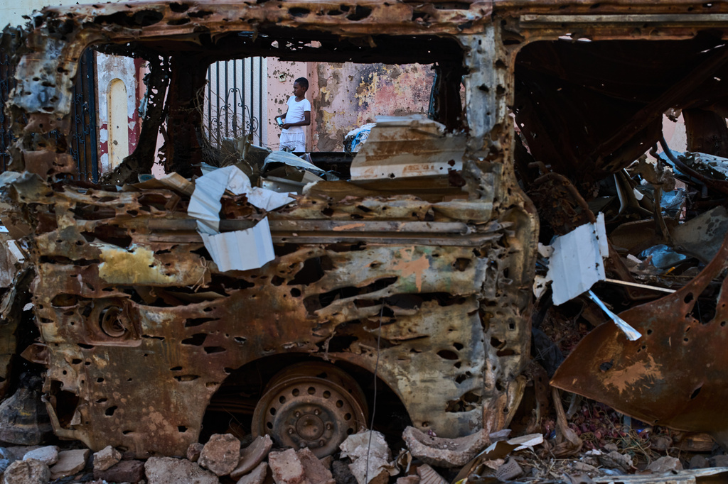 A boy is seen through the wreckage of a car in Omdurman, Sudan, on the outskirts of Khartoum, Friday, April 17, 2026. (AP Photo/Bernat Armangue)