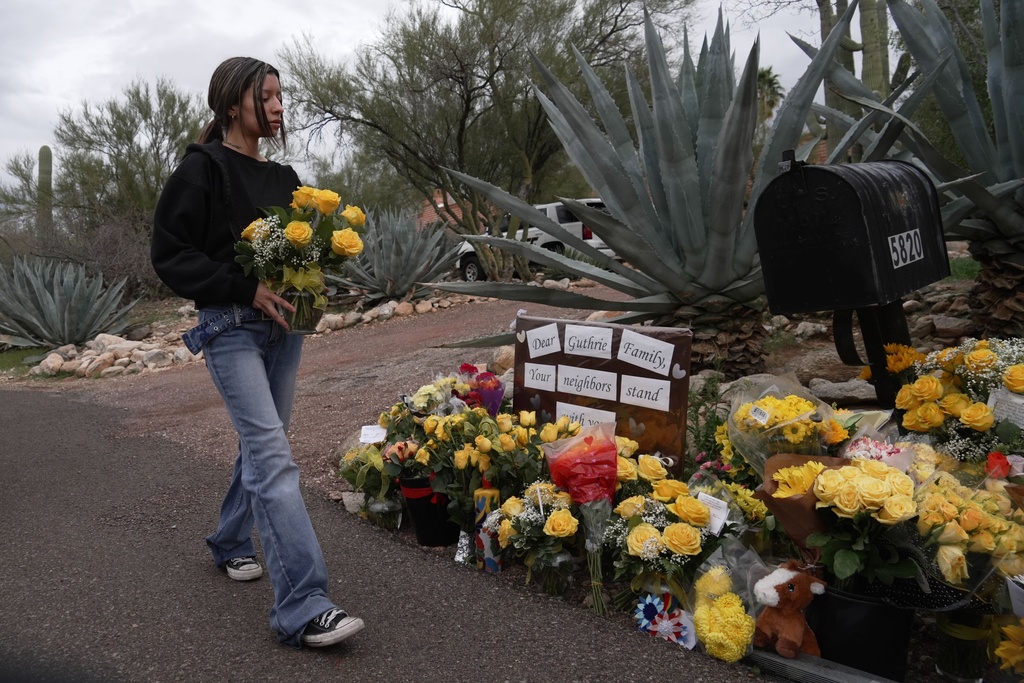 A person places flowers in front of Nancy Guthrie’s home in Tucson, Ariz., on Friday, Feb. 13, 2026. (AP Photo/Ty ONeil)