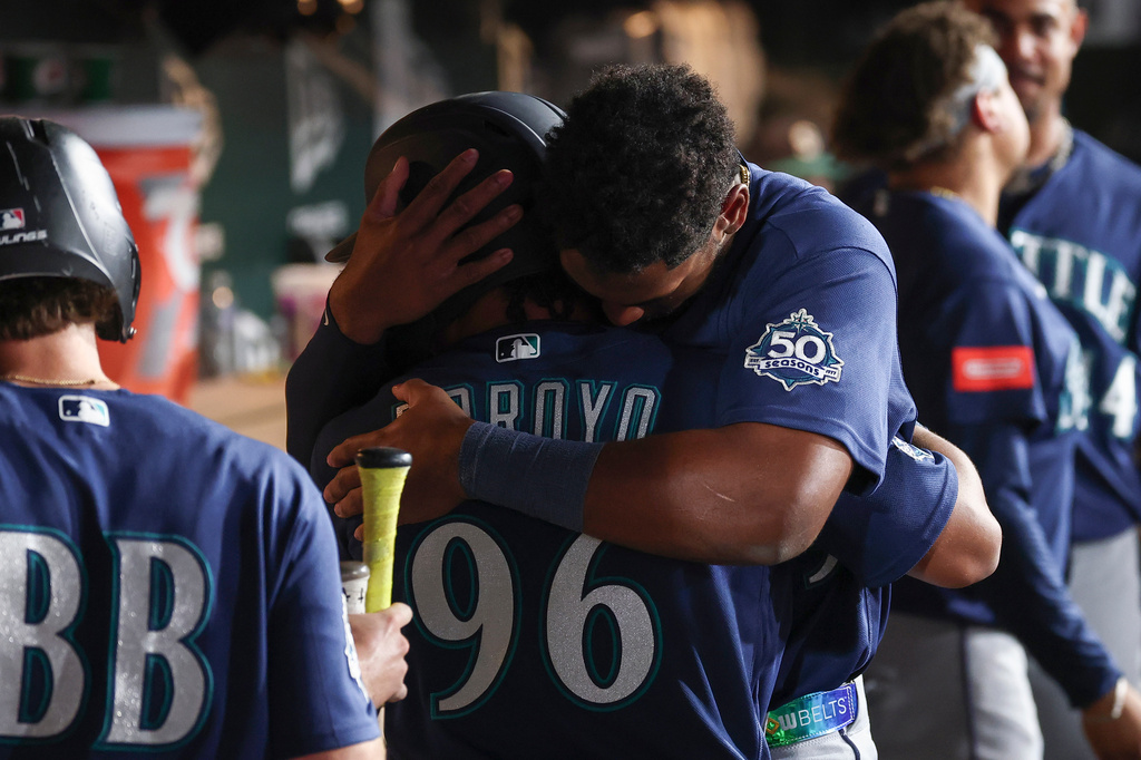 Seattle Mariners' Lazaro Montes, right, hugs Michael Arroyo (96) after his first major-league hit during the fourth inning of a baseball game against the Athletics Saturday, Sept. 12, 2026, in West Sacramento, Calif. (AP Photo/Sara Nevis)