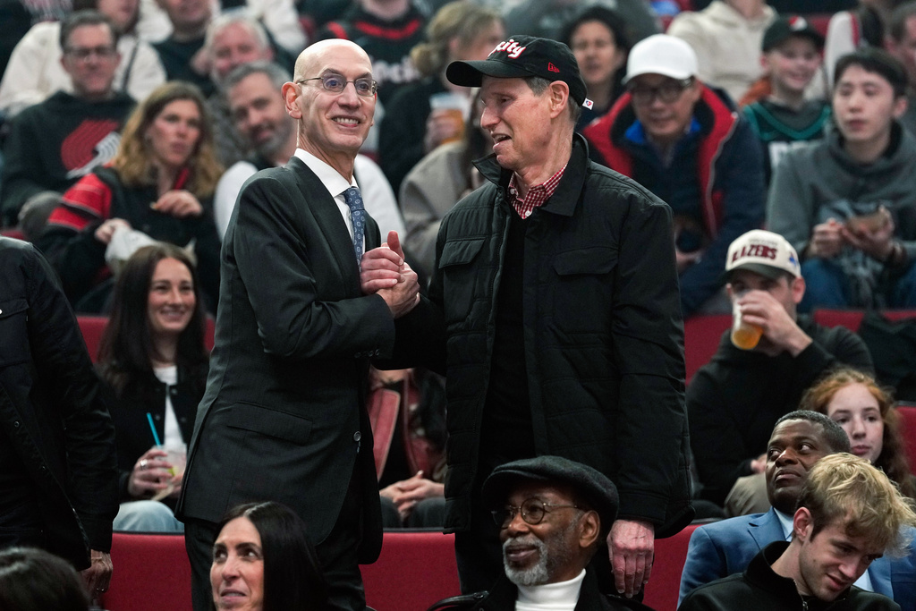 NBA commissioner Adam Silver greets Sen. Ron Wyden, D-Ore., as they take their seats before an NBA basketball game between the Portland Trail Blazers and the Utah Jazz, Friday, March 13, 2026, in Portland, Ore. (AP Photo/Jenny Kane)