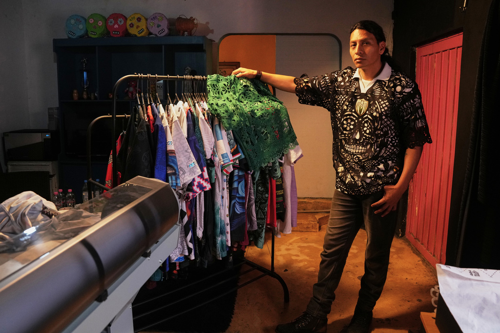 Designer Hugo Rosas poses for a photo with soccer jerseys, inspired by papel picado and traditional folk art, from his brand Mexclart, which he produces in his workshop in Cuautitlán Izcalli, Mexico, Monday, May 25, 2026. (AP Photo/Marco Ugarte)