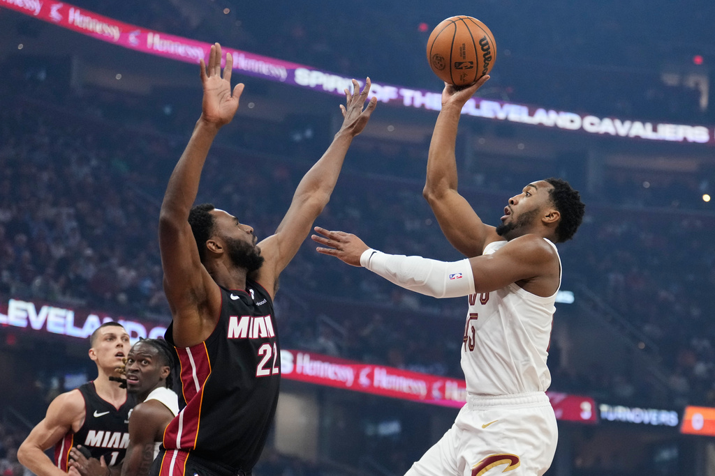 Cleveland Cavaliers guard Donovan Mitchell, right, shoots over Miami Heat forward Andrew Wiggins (22) in the first half of an NBA basketball game in Cleveland, Wednesday, March 25, 2026. (AP Photo/Sue Ogrocki)