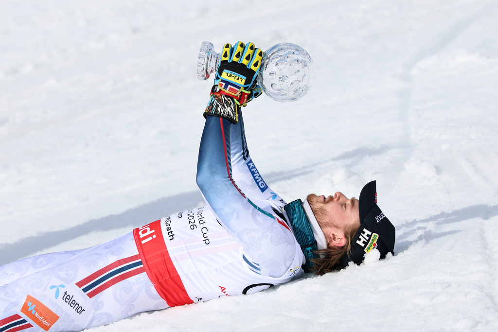Norway's Atle Lie McGrath lies on the snow, holding the globe trophy for the alpine ski, men's slalom discipline, at the Lillehammer World Cup Finals, in Hafjell, Norway, Wednesday, March 25, 2026. (AP Photo/Marco Trovati)