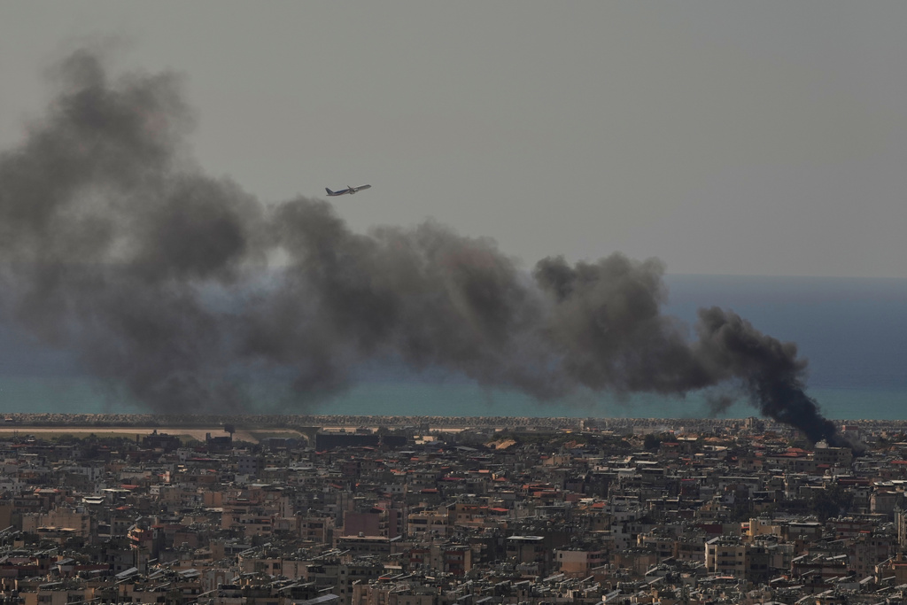 A Middle East Airlines plane takes off from Rafik Hariri International Airport as smoke rises from the site of an Israeli airstrike in Dahiyeh, Beirut's southern suburbs, Lebanon, Tuesday, March 17, 2026. (AP Photo/Hassan Ammar)