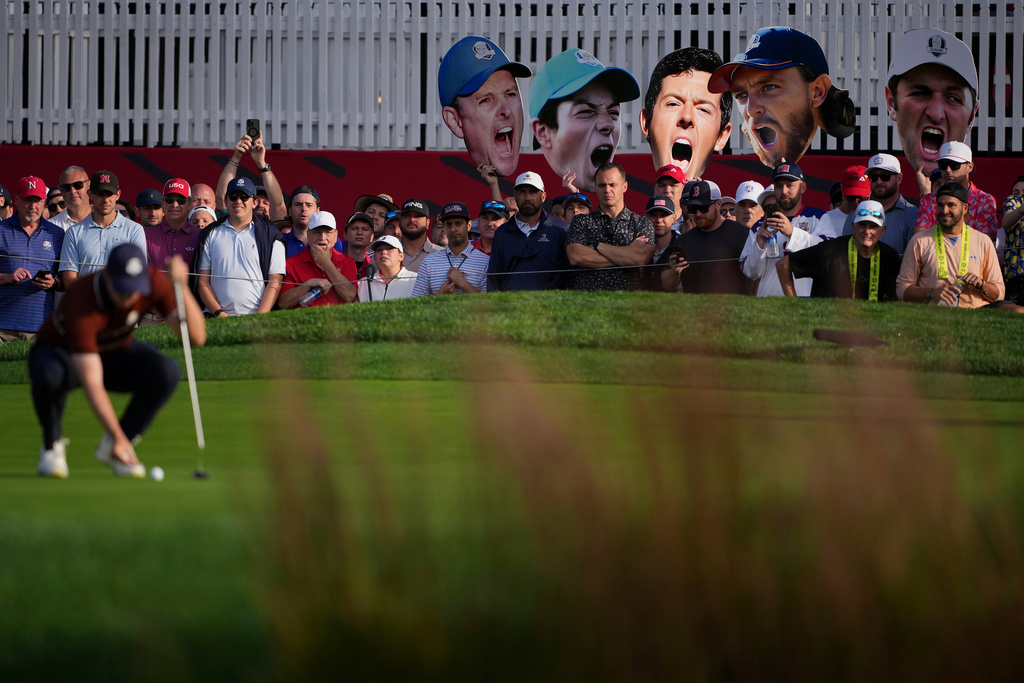 Fans hold up photos as Europe's Matthew Fitzpatrick lines up a putt on the seventh hole at Bethpage Black golf course during the Ryder Cup golf tournament, Saturday, Sept. 27, 2025, in Farmingdale, N.Y. (AP Photo/Matt Slocum)