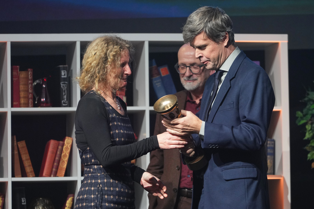 Canadian-Hungarian-British writer David Szalay receives the Booker Prize 2025 trophy for his book 'Flesh' from last year's winner Samantha Harvey during a ceremony at Old Billingsgate in London, Monday, Nov. 10, 2025. (AP Photo/Kirsty Wigglesworth)