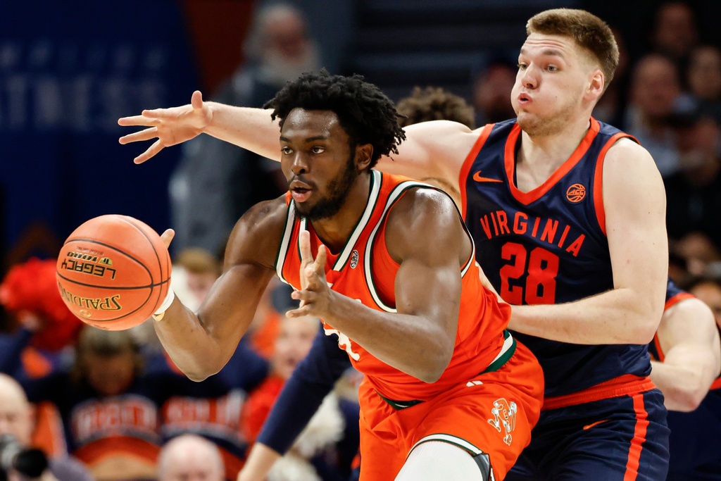 Miami center Ernest Udeh Jr., left, passes away from Virginia forward Thijs de Ridder during the first half of an NCAA college basketball game in the semifinals of the Atlantic Coast Conference tournament in Charlotte, N.C., Friday, March 13, 2026. (AP Photo/Nell Redmond)