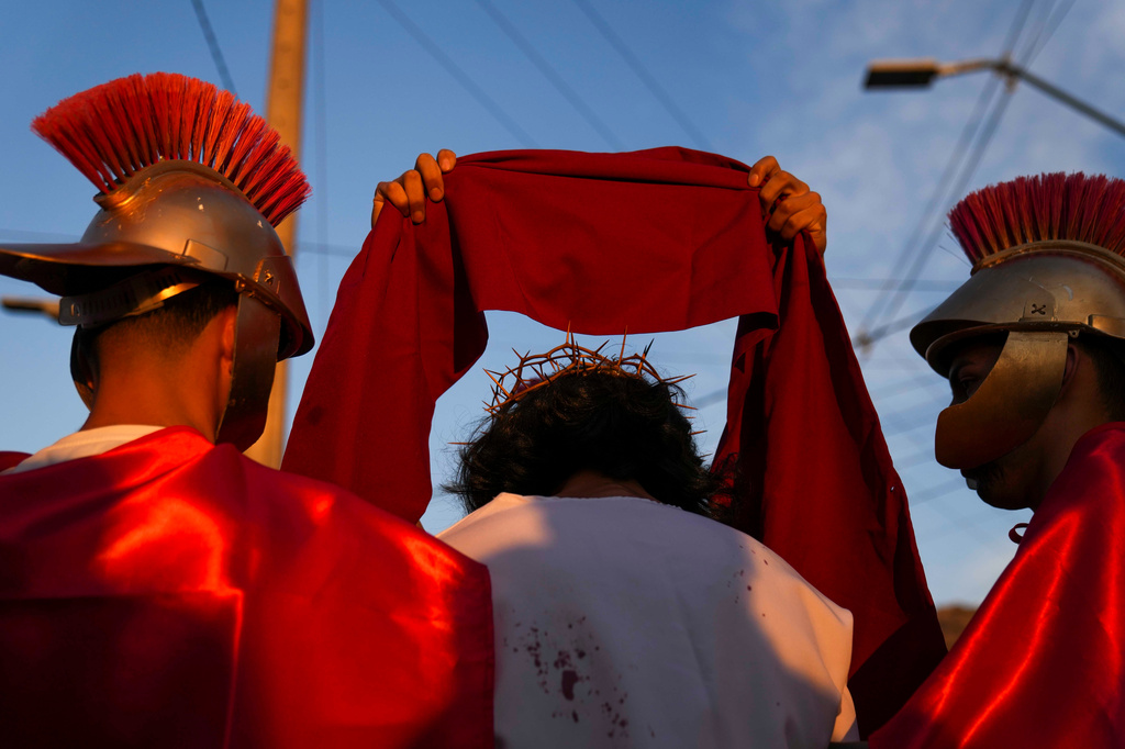 Roman soldiers dress David Sanchez, playing the role of Jesus Christ, with a crown and scarlet cloak to mock his claim as "King of the Jews", during a Way of the Cross reenactment as part of Holy Week celebrations, in Colina, Chile, on Good Friday, April 3, 2026. (AP Photo/Esteban Felix)