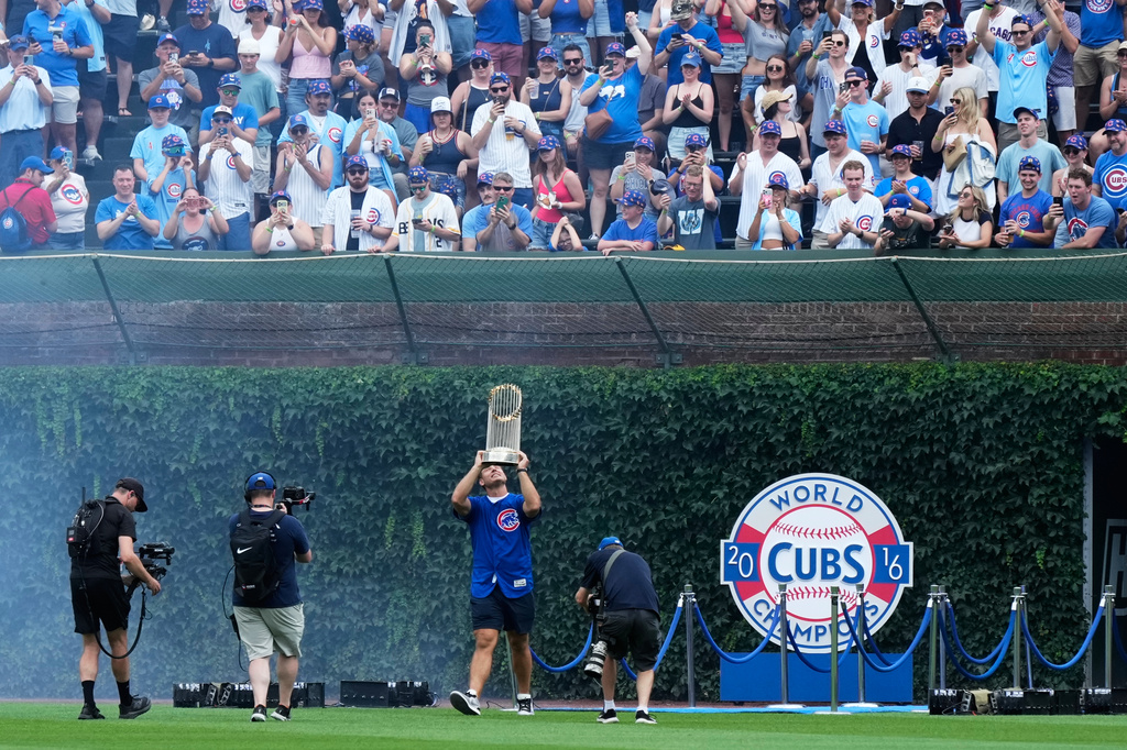 Former Chicago Cubs first baseman Anthony Rizzo holds up the 2016 World Series Championship trophy as his walks on the field before a baseball game between the Minnesota Twins and the Chicago Cubs in Chicago, Saturday, July 18, 2026. (AP Photo/Nam Y. Huh)
