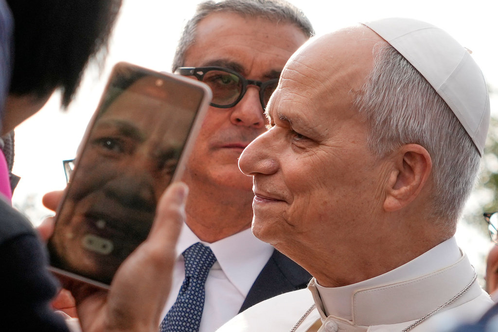 The head of Vatican Security, Gianluca Gauzzi Broccoletti, center, follows Pope Leo XIV as he visits the parish complex of Santa Maria della Presentazione on the outskirts of Rome, Sunday, March 8, 2026. (AP Photo/Gregorio Borgia)