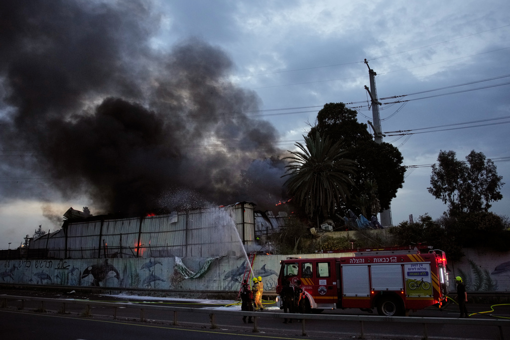 Firefighters try to extinguish flames at the site of a direct hit by an Iranian missile strike in Holon, central Israel, Friday, March 13, 2026. (AP Photo/Ohad Zwigenberg)