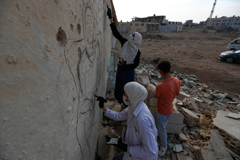 Syrian graffiti artists paint a mural on a war-damaged house in Daraya, on the outskirts of Damascus, Syria, Monday, Nov. 3, 2025. (AP Photo/Omar Sanadiki)