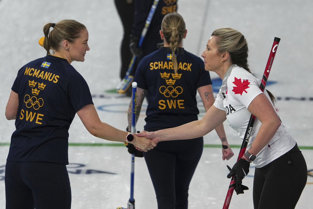 Canada's Emma Miskew and Sweden's Sara McManus shake hands after the women's curling round robin session, at the 2026 Winter Olympics, in Cortina d'Ampezzo, Italy, Tuesday, Feb. 17, 2026. (AP Photo/Misper Apawu)