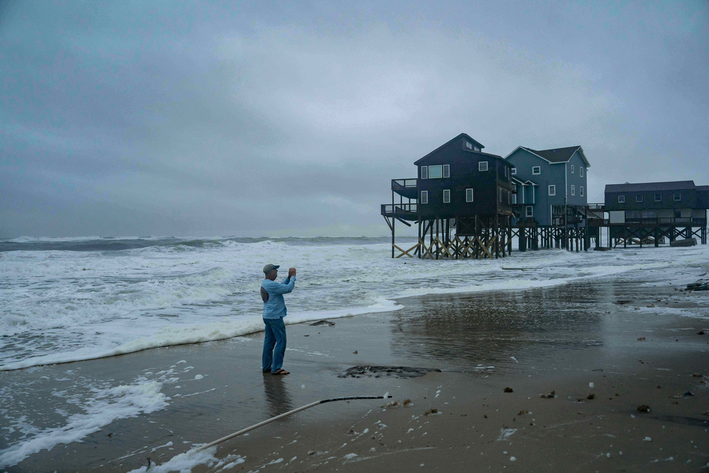 Local resident Lat Williams takes photos of his friend's houses to send to them in the midst of a storm, Sunday, Oct. 12, 2025, in Buxton, N.C. (AP Photo/Allison Joyce)