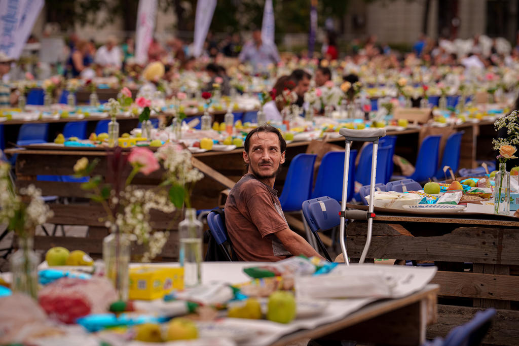A man sits at a 5-kilometer (3.1 miles) long "Uniting Table", made from recycled materials, during a Guinness World Record event to raise money for a children's psychiatric facility, in Bucharest, Romania, Saturday, Sept. 12, 2026. (AP Photo/Vadim Ghirda)