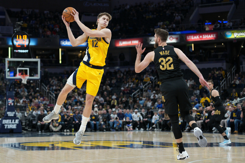 Indiana Pacers guard Johnny Furphy (12) pulls in a rebound in front of Cleveland Cavaliers forward Dean Wade (32) during the first half of an NBA basketball game in Indianapolis, Tuesday, Jan. 6, 2026. (AP Photo/AJ Mast)