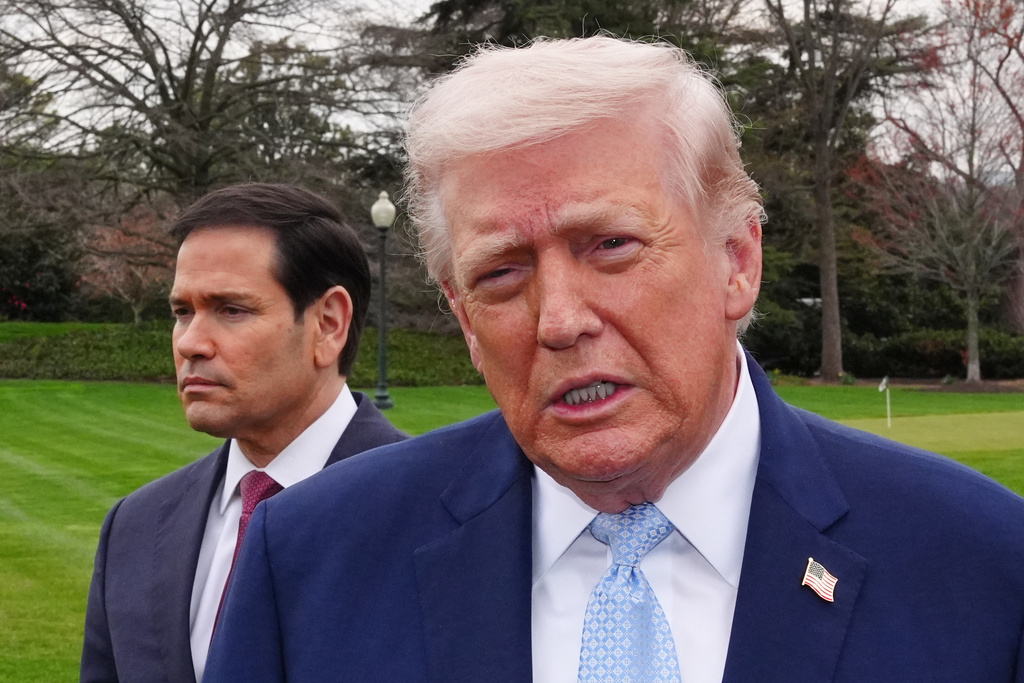 President Donald Trump speaks with reporters before departing on Marine One from the South Lawn of the White House, Friday, March 20, 2026, in Washington, as Secretary of State Marco Rubio listens. (AP Photo/Alex Brandon)
