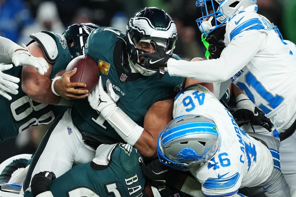Philadelphia Eagles quarterback Jalen Hurts (1) is stopped with the ball during the second half of an NFL football game by Detroit Lions linebacker Jack Campbell (46) and Lions cornerback Amik Robertson (21) Sunday, Nov. 16, 2025, in Philadelphia. (AP Photo/Matt Slocum)