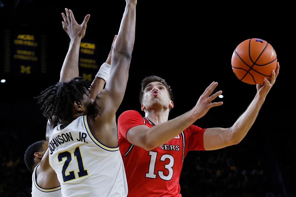 Rutgers guard Harun Zrno (13) goes to the basket against Michigan forward Morez Johnson Jr. (21) during the first half of an NCAA college basketball game Saturday, Dec. 6, 2025, in Ann Arbor, Mich. (AP Photo/Duane Burleson)