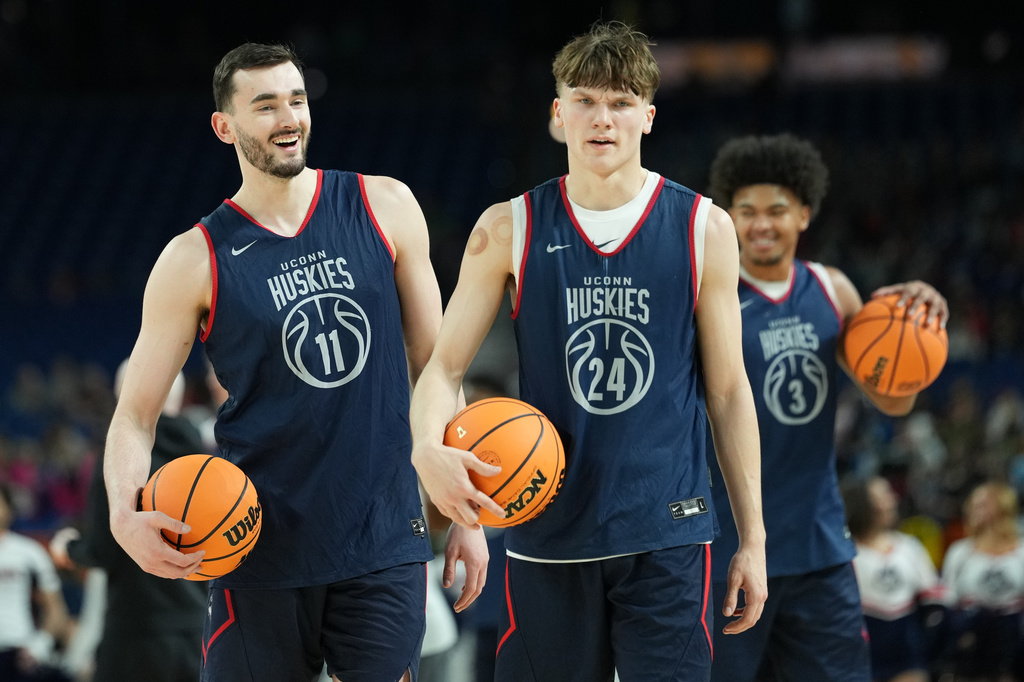 UConn's Alex Karaban (11) laughs alongside teammate Braylon Mullins (24) and Jaylin Stewart (3) during practice ahead of a national semifinal NCAA college basketball tournament game against Illinois at the Final Four, Friday, April 3, 2026, in Indianapolis. (AP Photo/Abbie Parr)