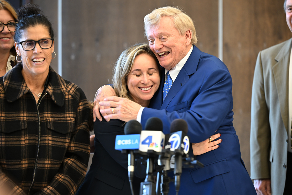Attorney Russell Hardin Jr. hugs Tyler Skaggs' widow, Carli Skaggs, center, as Skaggs mother's Debbie smiles, at left, after a settlement was reached in the wrongful death lawsuit by the family of the Los Angeles Angels pitcher Friday, Dec. 19, 2025, in Orange County Superior Court, in Santa Ana, Calif. (AP Photo/William Liang)