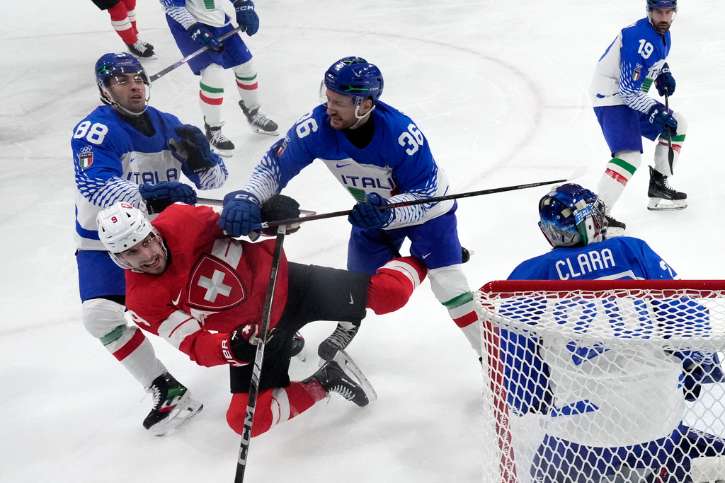 Switzerland's Damien Riat (9) challenges with Italy's Cristiano Digiacinto (36) during a men's ice hockey qualification playoff game between Switzerland and Italy at the 2026 Winter Olympics, in Milan, Italy, Tuesday, Feb. 17, 2026. (AP Photo/Darko Bandic, Pool)