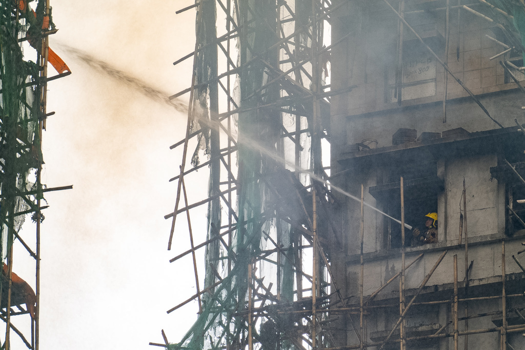 A firefighter works to extinguish a fire that broke out at Wang Fuk Court, a residential estate in the Tai Po district of Hong Kong's New Territories, Thursday, Nov. 27 2025. (AP Photo/Chan Long Hei)