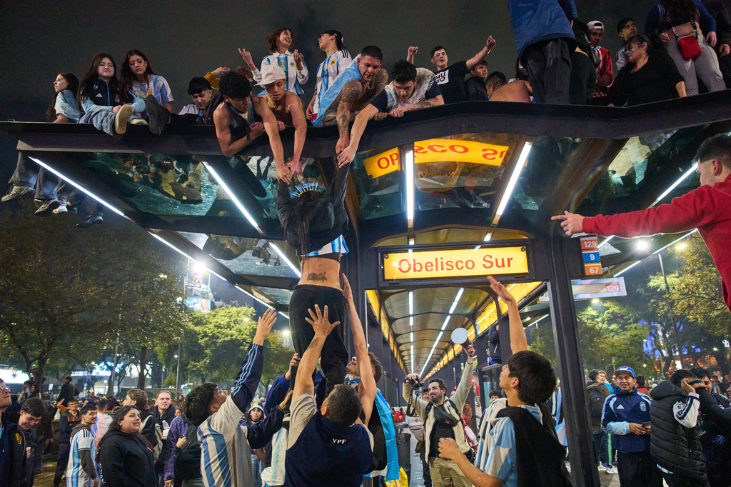 Fans climb onto a bus stop during celebrations of Argentina's victory over England in a World Cup semifinal soccer match in downtown Buenos Aires, Argentina, Wednesday, July 15, 2026. (AP Photo/Rodrigo Abd)