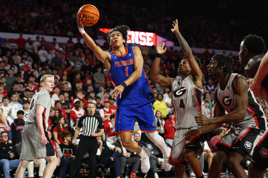 Florida guard Xaivian Lee (1) shoots against Georgia guard Marcus Millender (4) and forward Dylan James, right, during the first half of an NCAA college basketball game, Saturday, Feb. 11, 2026, in Athens, Ga. (AP Photo/Colin Hubbard)