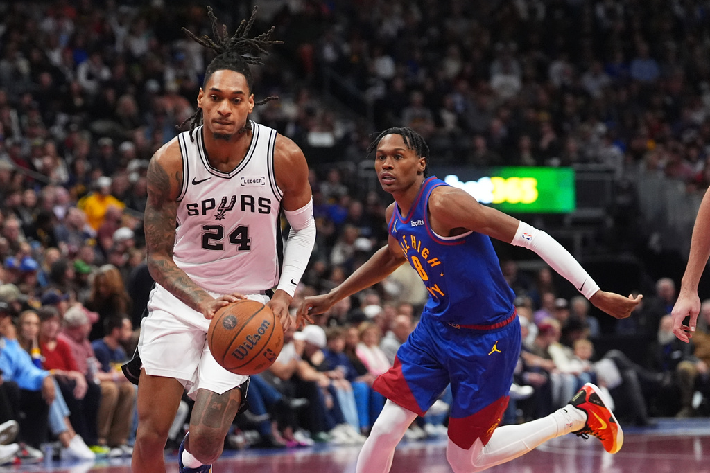 San Antonio Spurs guard Devin Vassell, left, drives the lane past Denver Nuggets guard Peyton Watson in the first half of an NBA Cup basketball gam,e Friday, Nov. 28, 2025, in Denver. (AP Photo/David Zalubowski)