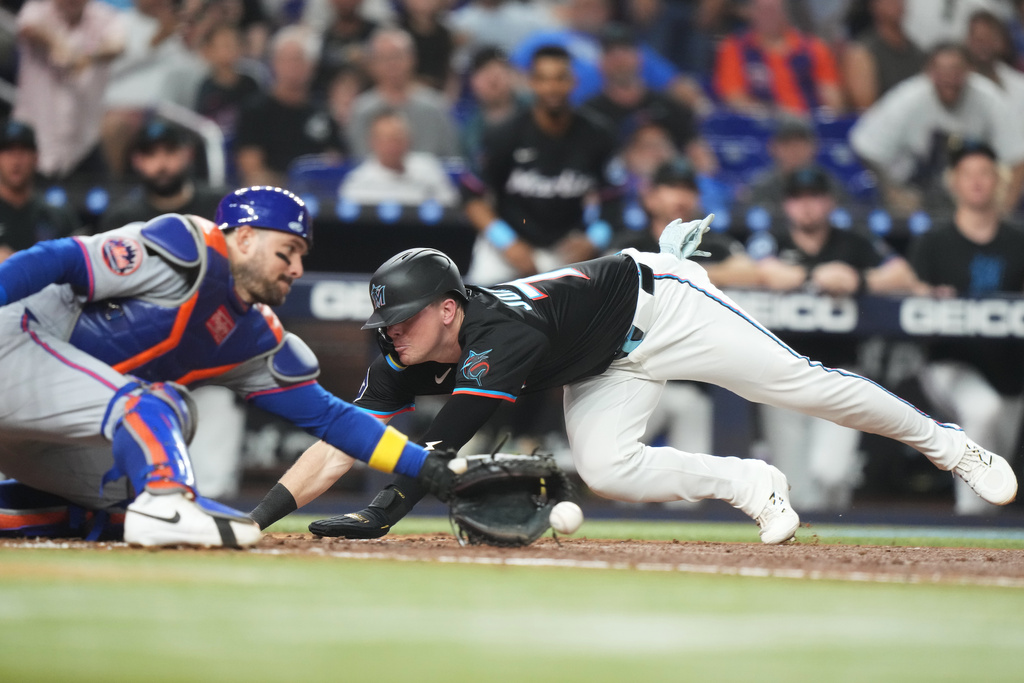 Miami Marlins' Troy Johnston, right, beats the throw to New York Mets catcher Luis Torrens, left, to score on a RBI triple hit by Heriberto Hernandez during the of a baseball game, Friday, Sept. 26, 2025, in Miami. (AP Photo/Lynne Sladky)