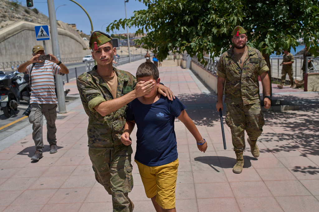 A 12-year-old unaccompanied minor who crossed into Spain is escorted by a Spanish soldier to the Spain-Morocco border from the Spanish enclave of Ceuta, Monday, Aug. 3, 2026. The forced deportation of the unaccompanied minor was stopped by a high-ranking official a few meters before the child reached the border after residents and journalists said the migrant was a minor. (AP Photo/Bernat Armangue)