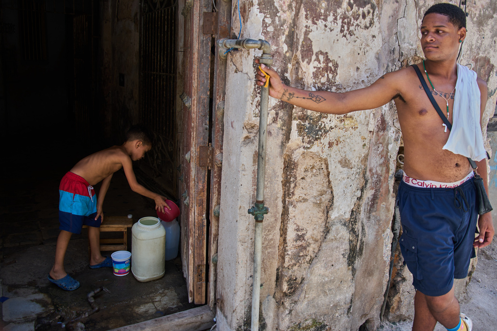 A youth collects water from the bottom floor of a residential building, during a blackout that stopped the water pump, in Havana, Cuba, Tuesday, July 14, 2026. (AP Photo/Ramon Espinosa)